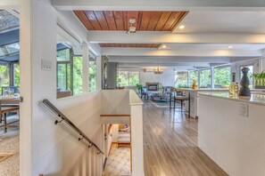 Eine moderne Küche mit einer zentralen Kochinsel, ein Essbereich mit einem runden Tisch und eine Treppe, die zu einer oberen Ebene führt.