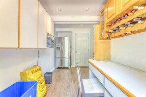 A narrow kitchen with wooden cabinets, a stainless steel refrigerator, and a wine rack. - Modern Mid-Century Home - Solarium, Deck and Jacuzzi (North Vancouver)