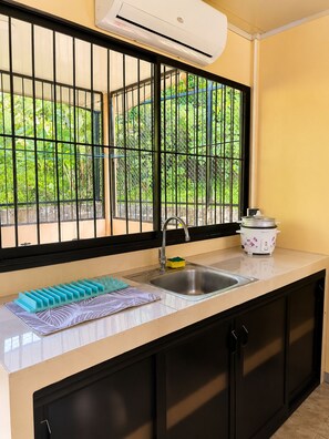 A kitchen with a window, sink, and a rice cooker.