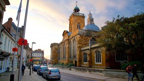 A street with parked cars, a church with a dome, and a building with a clock tower. - Modern | Central | Park Free | Northants (West Northamptonshire)