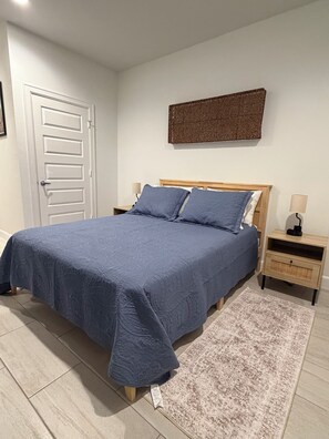 A bedroom with a bed, nightstands, a door, and a wall-mounted artwork. - Private Houston Suite.  Separate Entry, Full Bath & Mini Kitchen.  Near It All (Houston)