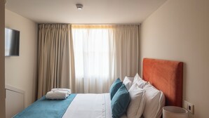 Ein Hotelzimmer mit Bett, Vorhängen, Fernseher und Lampe.