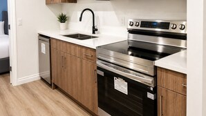 Una cocina moderna con electrodomésticos de acero inoxidable, armarios de madera y encimera blanca.