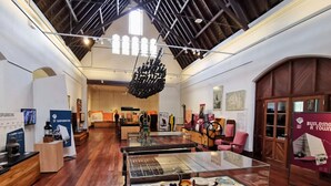 An interior with a high ceiling, wooden beams, and a glass display case with items. - Casa Bella – Stylish Art Deco Retreat in the Heart of East Bunbury (East Bunbury)