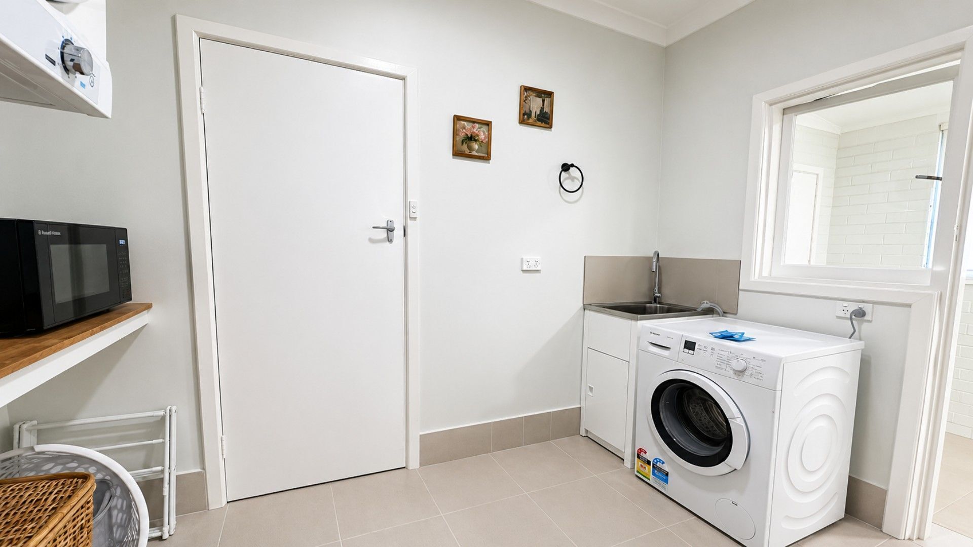 A laundry room with a washing machine, a microwave, and a door.