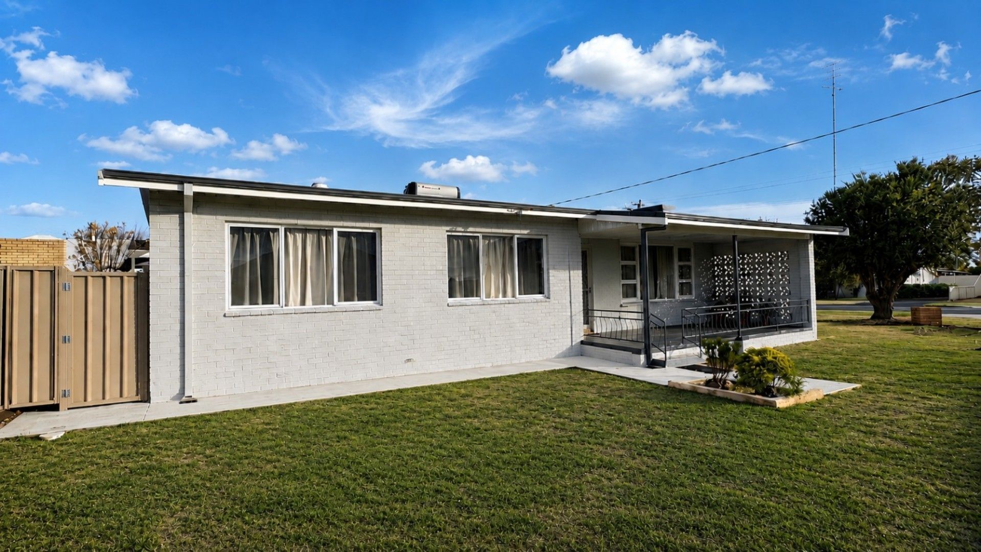 A single-story house with a covered porch, a fenced yard, and a clear sky.