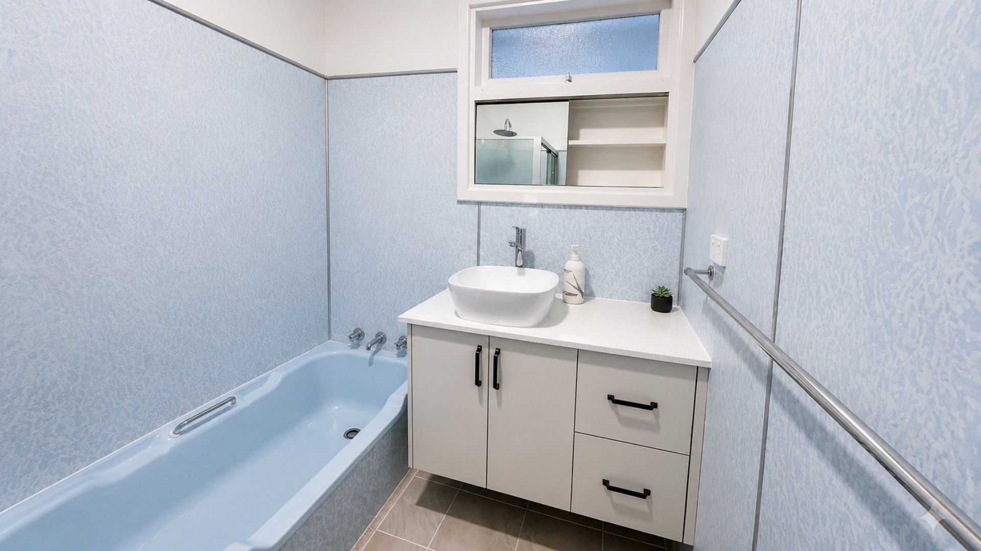A bathroom with a bathtub, a sink, and a mirror above the sink.