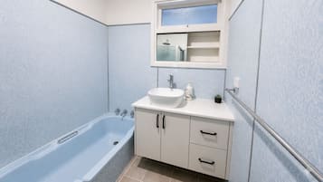 A bathroom with a bathtub, a sink, and a mirror above the sink.