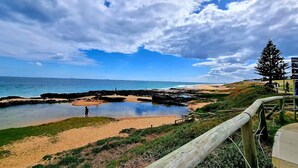 A coastal beach with rocky formations, a wooden walkway, and a clear view of the ocean. - Casa Bella – Stylish Art Deco Retreat in the Heart of East Bunbury (East Bunbury)