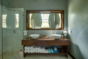 A bathroom with a large mirror, two sinks, and a wooden vanity.