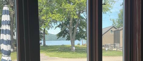 A view through a window of a room with a chair and an umbrella outside.