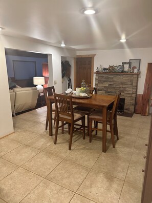 A dining area with a wooden table and chairs, a stone fireplace, and a door leading to another room. - Cozy 2-bedroom lake view house in charming Poynette with AC (Poynette)