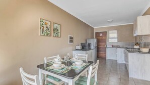 A dining area with a table set for four, a kitchen with modern appliances, and a door with a 'No Entry' sign. - No1 Airville Sol, 9 min Drive to Cresta Mall (Johannesburg)