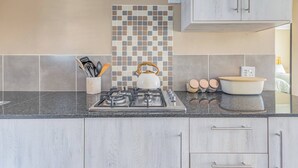 A kitchen with a gas stove, a kettle, a bowl, and a utensil holder. - No1 Airville Sol, 9 min Drive to Cresta Mall (Johannesburg)