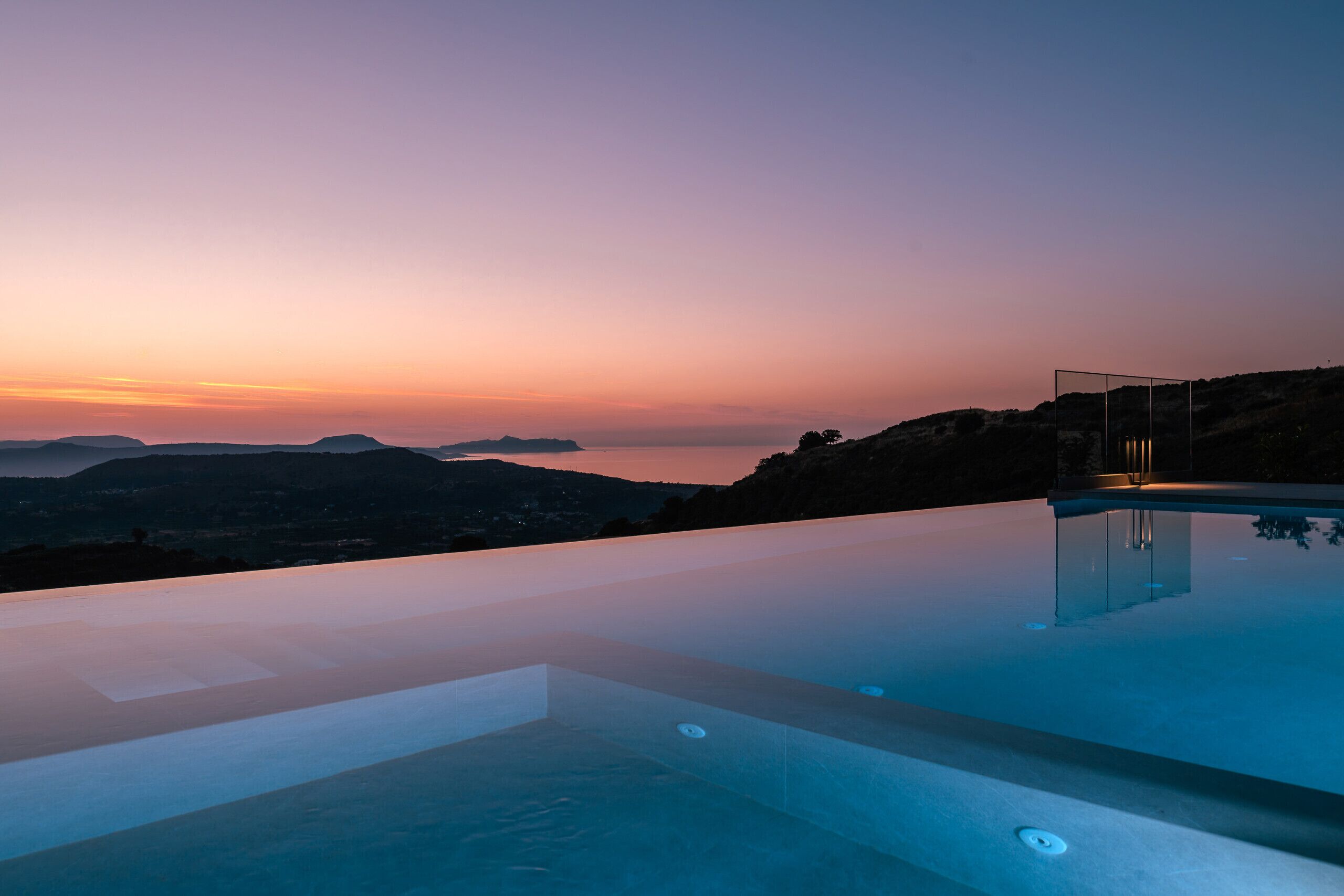 Une piscine à débordement offrant une vue imprenable sur le coucher de soleil sur les collines.