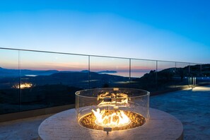 Ein Feuerkorb mit klarer Glasabdeckung auf einem Balkon mit Blick auf ferne Berge.