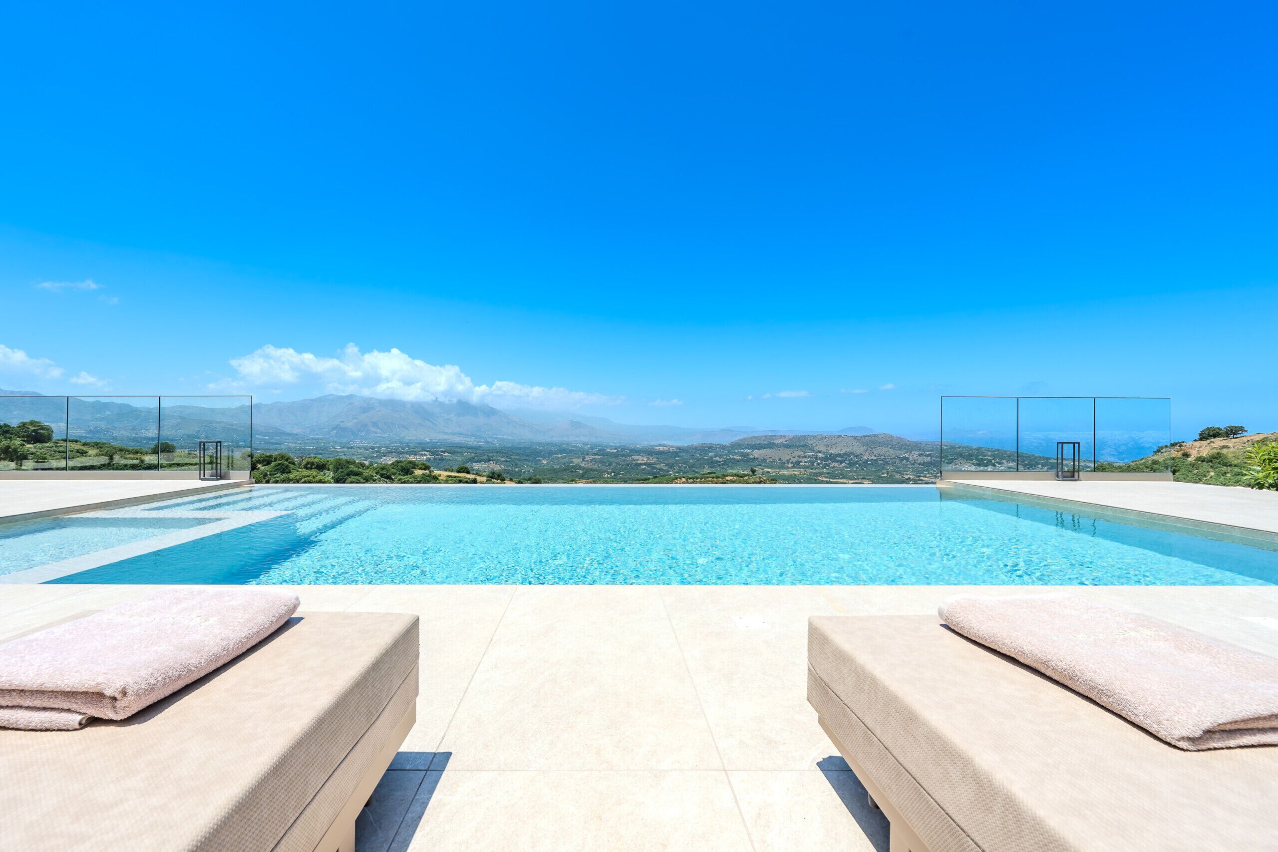 A pool with two lounge chairs and a view of the landscape.