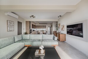 Ein modernes Wohnzimmer mit Ecksofa, Couchtisch und Fernseher.