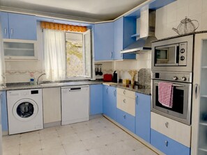 A compact kitchen with a washing machine, a microwave, and an oven. - Amarena Apartment 20812 (Argoños)