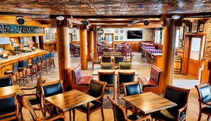 A restaurant with wooden tables and chairs, a bar area, and a television screen.