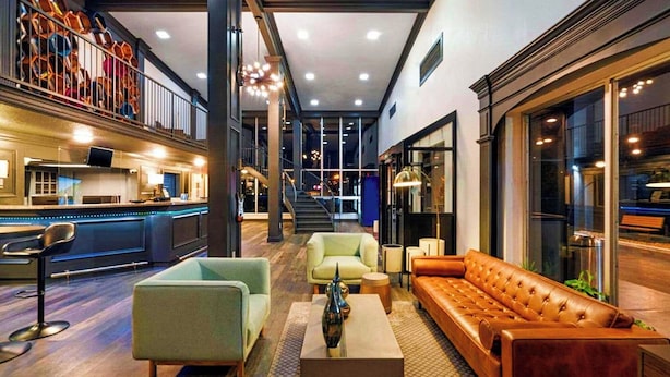 A spacious lobby with a bar area, seating arrangements, and a staircase leading to upper floors. - Bposhtels Nashville (Nashville)