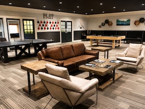 Ein stilvoller Lounge-Bereich mit Billardtisch, Ledersofa und Spieltischen.