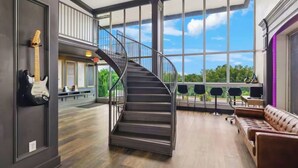 A spacious interior with a spiral staircase, large windows offering a view of the outdoors, and a seating area with a leather couch. - Bposhtels Nashville (Nashville)