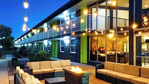 An outdoor seating area with sofas and a fire feature, a building with a balcony, and string lights. - Bposhtels Nashville (Nashville)