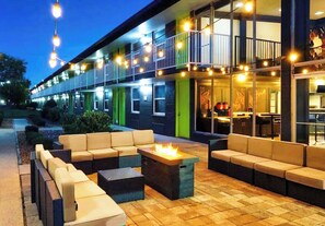 An outdoor seating area with sofas and a fire feature, a building with a balcony, and string lights. - Bposhtels Nashville (Nashville)