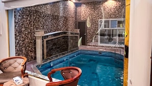 Uma área de spa com hidromassagem, paredes de pedra e duas cadeiras de madeira.
