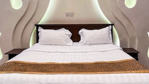 Quarto moderno com cama grande, cabeceira de madeira e design de parede único com luminárias.