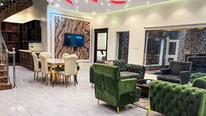 Sala moderna com área de jantar, televisão fixada em parede de mármore e escada que leva a outro nível.