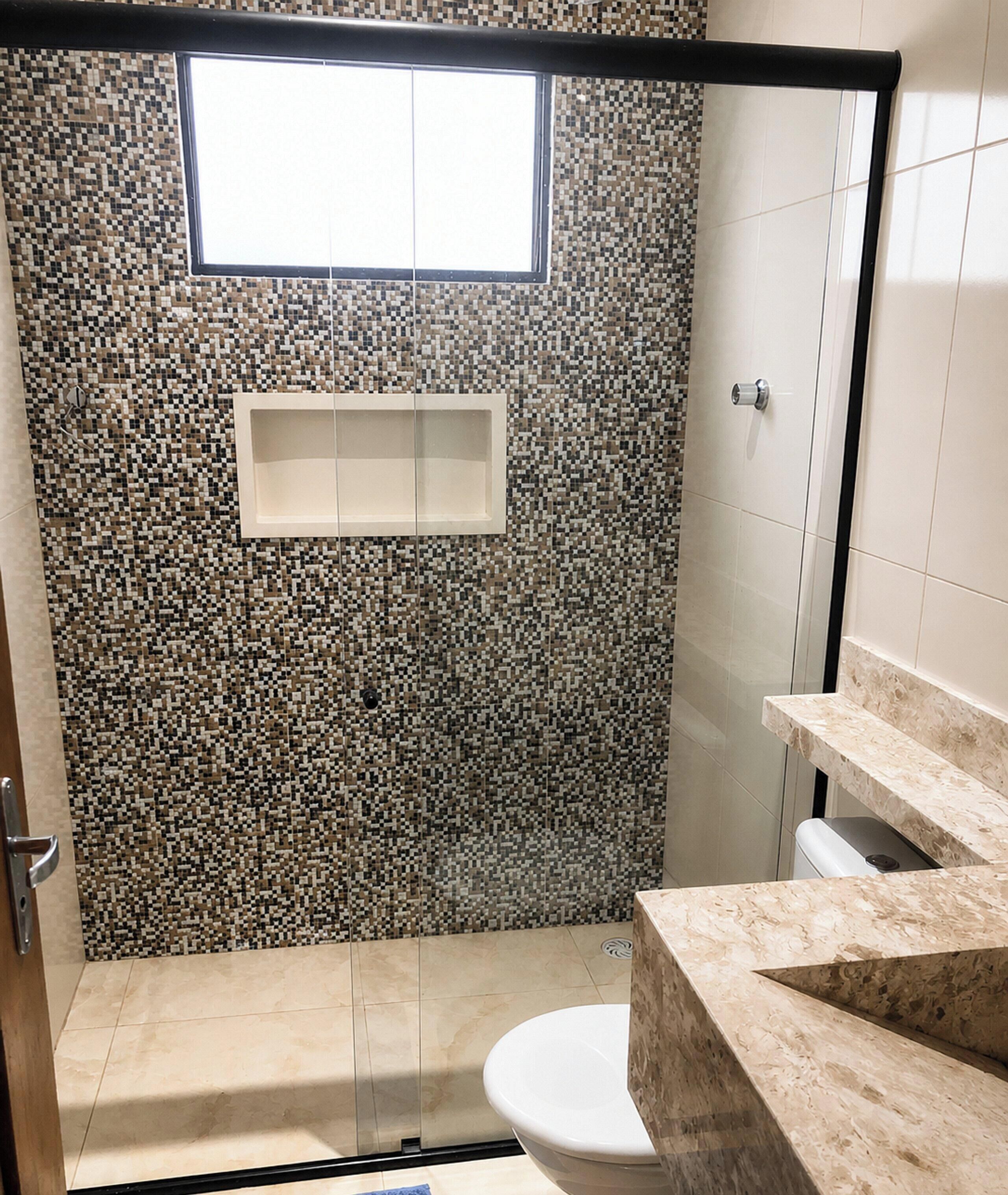 A bathroom with a shower, toilet, and a small window.