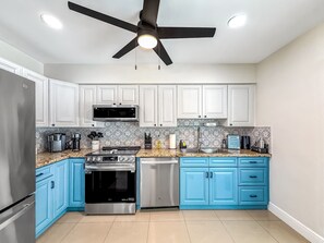 A kitchen with white cabinets, a black ceiling fan, a stainless steel refrigerator, a microwave, a stove, and a dishwasher. - Heated Pool! Tropical Backyard! Hammock+Ping-Pong! (Oakland Park)