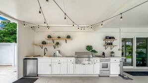 Een moderne keuken met witte kastjes, een roestvrijstalen fornuis en hangende lichtjes.