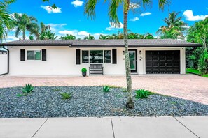 A single-story house with a garage, a small porch, and a gravel driveway. - Heated Pool! Tropical Backyard! Hammock+Ping-Pong! (Oakland Park)