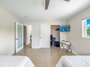 A hotel room with two beds, a TV on the wall, a window with a view, and a closet with hanging clothes. - Heated Pool! Tropical Backyard! Hammock+Ping-Pong! (Oakland Park)