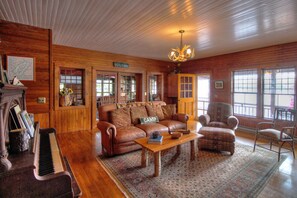 Ein Holzinterieur mit Klavier, Ledersofa, Ohrensessel und einem 'Welcome'-Schild.