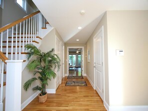 A hallway with wooden flooring, white walls, a staircase with wooden railings, and a potted plant. - Surf City Oceanfront Property (Surf City)