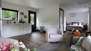 A modern hotel room with a kitchenette, a bed, a seating area, and a view of the outdoors. - Steps from the Lake- Sauna + Hot Tub. Unit #2 (Jones)