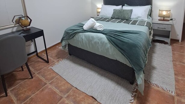A bedroom with a bed, bedside tables, a desk, and a chair.
