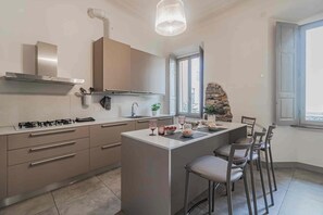 Una cocina moderna con una isla central, electrodomésticos de acero inoxidable y una pared de acento de piedra.