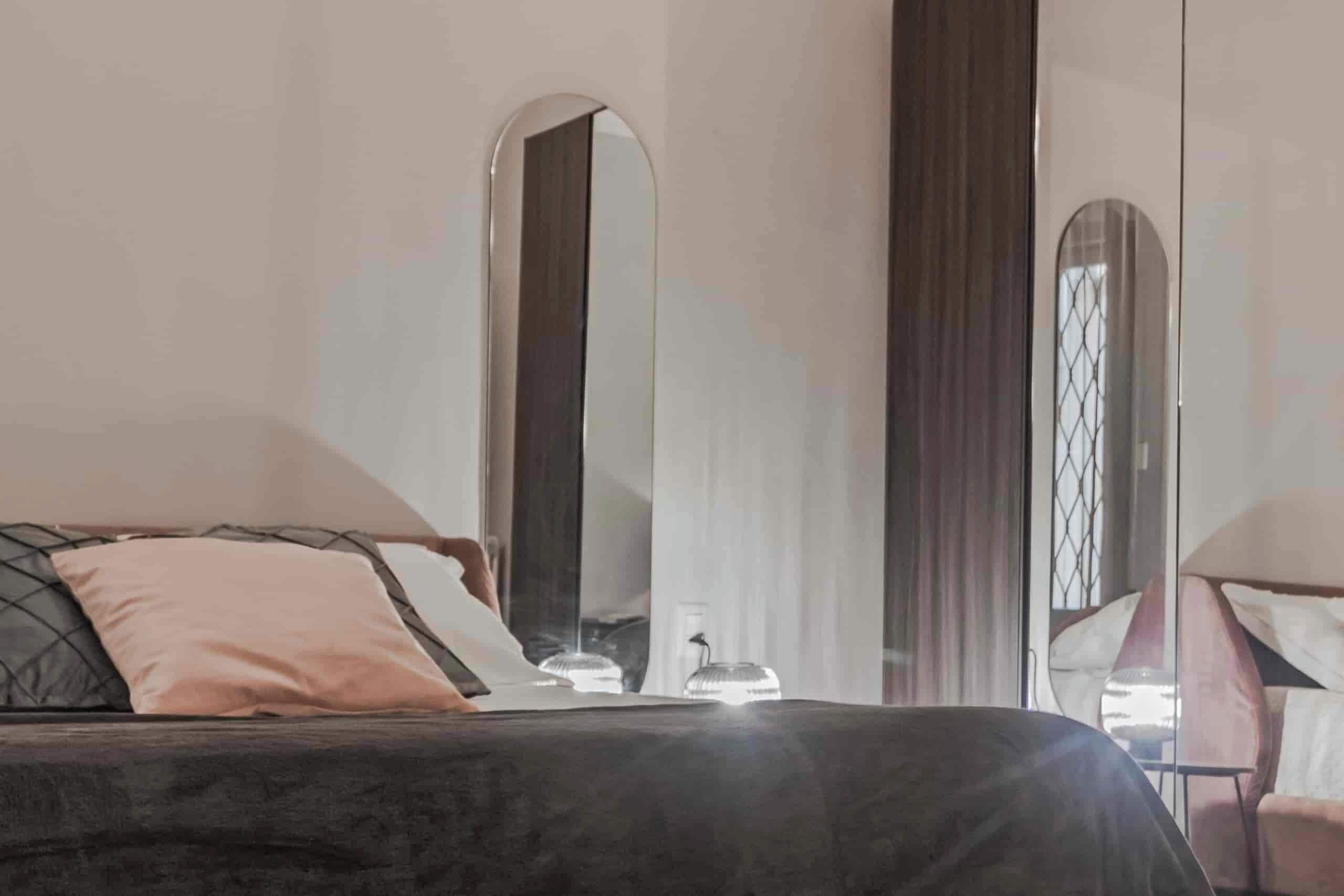 Une chambre à coucher avec un lit, une chaise et un grand miroir.
