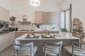 A modern kitchen with a central island, stainless steel appliances, and a stone accent wall. - [Como Historic Center] White Lotus Luxury Suites (Como)