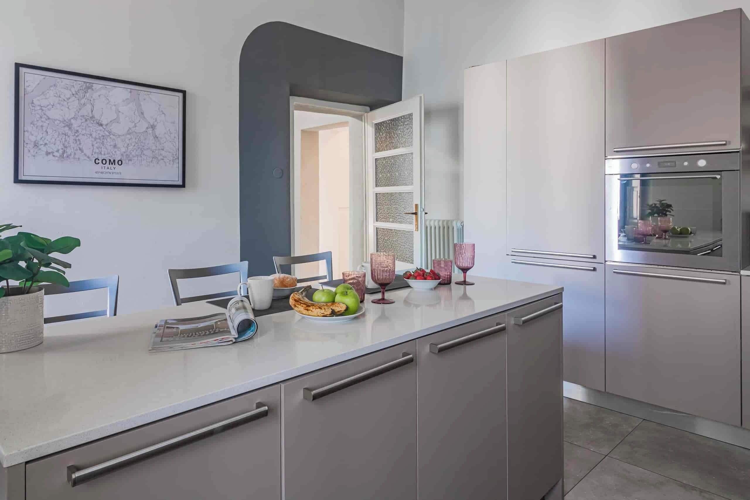 A modern kitchen with a marble backsplash, a dining area with a table set for two, and a cityscape artwork on the wall.