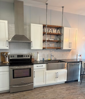 A modern kitchen with white cabinets, stainless steel appliances, and a wooden backsplash.