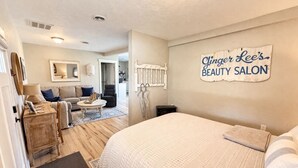 A bedroom with a bed, a dresser, a mirror, and a sign for Ginger Lee's Beauty Salon. - Thompson Cottage - Sleeps 4 (Sedro-Woolley)