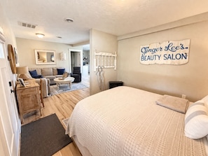 A bedroom with a bed, a dresser, a mirror, and a sign for Ginger Lee's Beauty Salon.