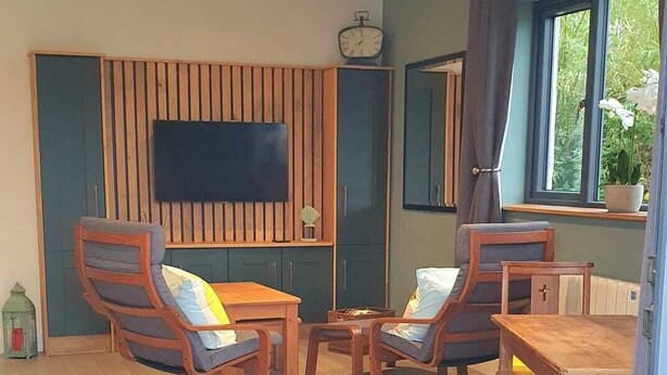Ein Wohnzimmer mit Fernseher, Holzmöbeln und einem Fenster.