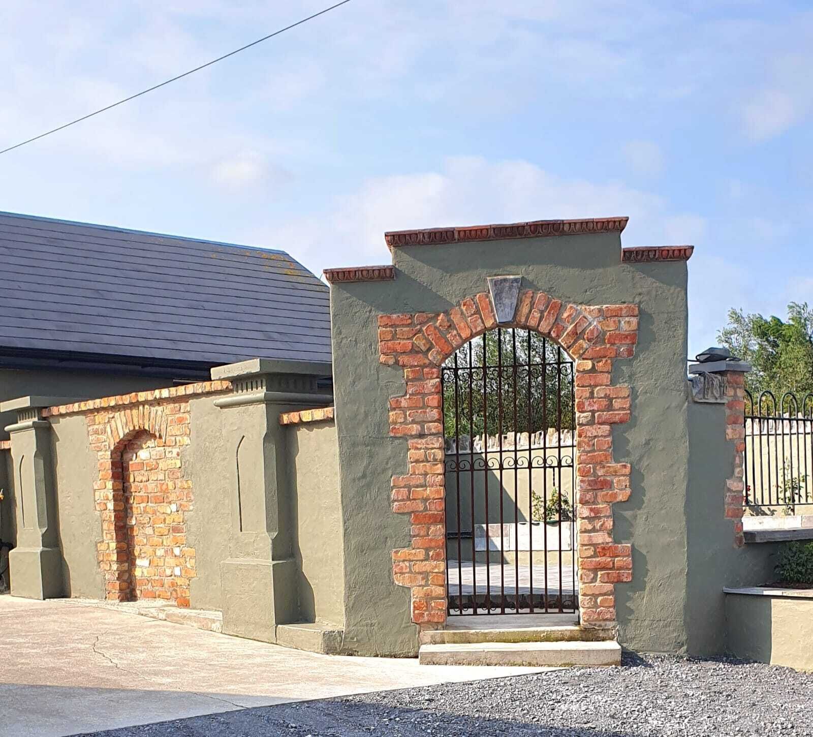 A gated entrance with a brick archway and a metal gate.